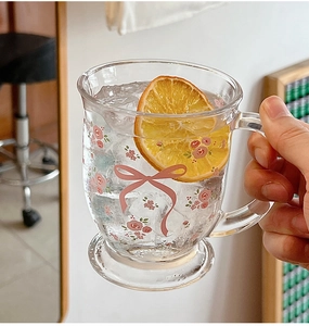 Vue détaillée d'une tasse en verre à fleurs avec nœud, anse et une tranche d'orange séchée