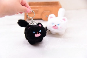 Close-up of black and white plush cat keychains with metal bells and detailed embroidery