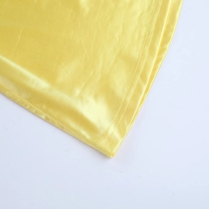 Macro detail of yellow satin dress showing fine double-row stitching and glossy fabric texture