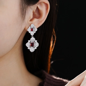 Detail view of flower-shaped silver earrings featuring red rubies and cubic zirconia