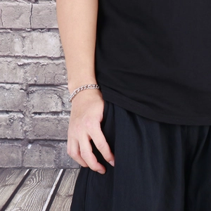 Detail of silver heavy Cuban link bracelet with studded texture on a male model's wrist
