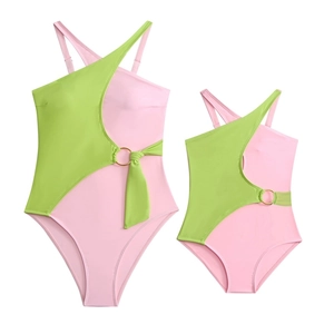 Detail of matching mother-daughter one-shoulder swimsuits in pink and green with gold ring