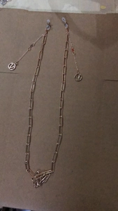 Detailed macro view of rose gold glasses chain with V-logo charms and lobster clasps