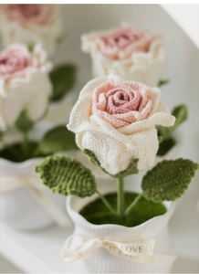 Close-up of handmade crochet pink rose in a pot with Love is Eternal decorative ribbon