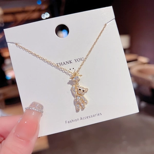 Detail of a sparkling gold bear pendant encrusted with white crystals on a dainty chain
