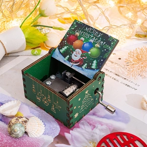 Detailed view of a green hand-cranked wooden music box with Santa Claus and festive carvings