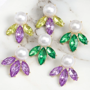 Close-up of luxury pearl earrings with colorful crystals on a marble surface