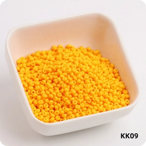Macro shot of 3mm bright yellow round glass seed beads in a white square container