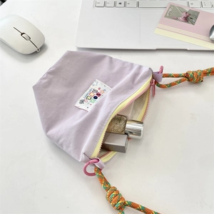 Detail of purple nylon crossbody bag featuring colorful letter patches and yellow lining
