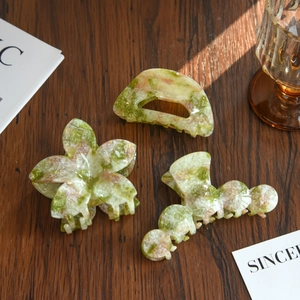 Three-piece hair claw set with marble and floral patterns on a dark wooden surface