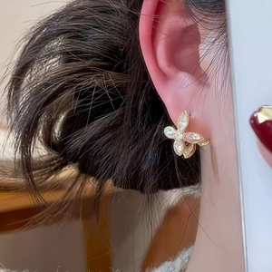 Gros plan détaillé d'une boucle d'oreille papillon dorée ornée de zircons sur le modèle