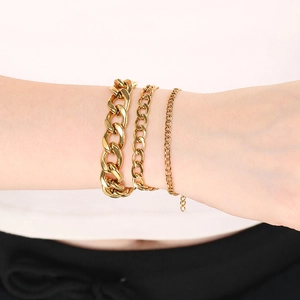Three gold stainless steel NK link chains worn by a model in a professional studio setting