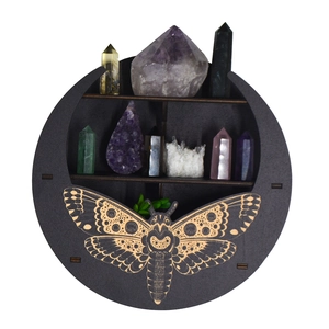 Detailed view of a black circular wooden shelf with bohemian moth carving and crystals