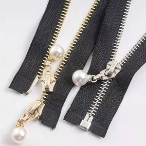 Detail of high-gloss ABS pearl zipper pull with rhinestone ring on black fabric tape