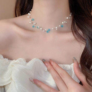 Detail of layered necklace featuring white pearls and sky blue crystals on model neckline