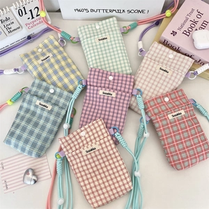 Detailed view of plaid fabric phone pouches in various pastel colors with thick cord straps
