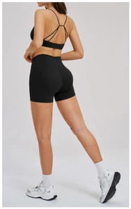 Detail of cross-back strap design on black sports bra and high-waisted shorts