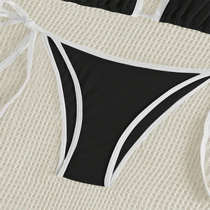 Detail of black bikini bottom featuring white piping and adjustable side-tie design