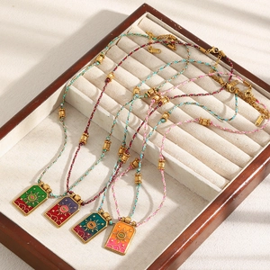 Macro detail of 18K gold plated sun tarot necklaces with colorful enamel on velvet tray