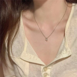Close-up of a delicate silver cherry pendant necklace on a model wearing a shirt