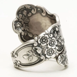 Macro view of vintage floral relief patterns on a wide silver-toned spoon ring band