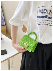 Green rhombic jelly bag with bead handle and gold chain strap shown on a model