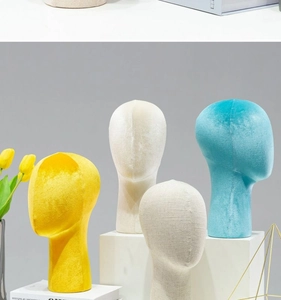 Velvet head forms for wig and hat display on decorative stone pedestals and books