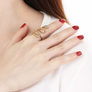 Gros plan d'une bague serpent dorée avec strass blancs portée sur le doigt