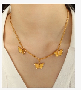 Close-up of golden paperclip chain necklace featuring three zircon butterfly pendants