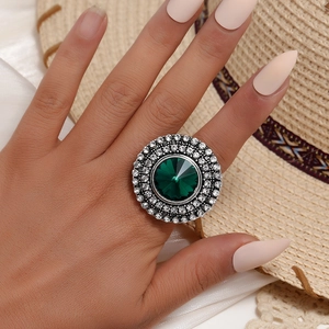Close-up of vintage silver ring with emerald green stone and sparkling zircon details