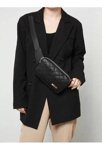 Front view of model wearing a black quilted PU leather crossbody fanny pack with gold zippers
