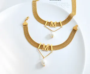 Detailed close-up of woven gold mesh band with a bold M letter and elegant pearl drop