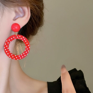 Close-up of red and white polka dot resin hoop earrings on model for retro style