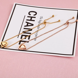 Détail de bracelets ajustables avec pendentif triangle en or et or rose et chaîne vénitienne