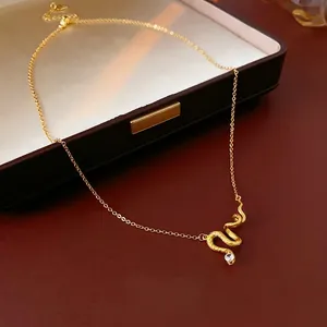 Gold-plated snake necklace with scales and cubic zirconia pendant on jewelry box