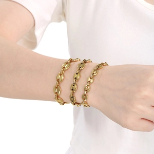 Close-up of gold layered coffee bean pig nose chain bracelets on a model wrist