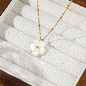 Detail of gold-plated stainless steel necklace with white shell flower pendant in a jewelry box