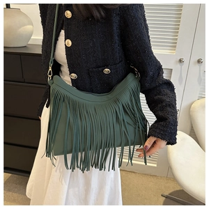 Detailed view of long tassels on dark green bohemian bucket bag with slim leather strap