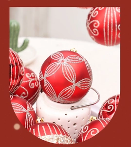 Détail d'une boule de Noël rouge avec des motifs floraux pailletés dorés et anneau de suspension