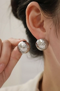 Detail of silver hammered texture ball stud earring on ear showing polished metallic finish