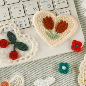 DIY cherry and tulip embroidery patches on white keyboard and denim background