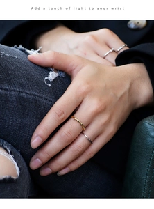 Detailed view of geometric diamond-cut gold and silver rings worn on fingers