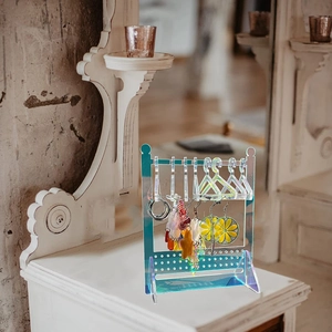 Rainbow acrylic earring display stand with mini clothes hangers on white wooden desk