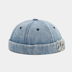 Faded blue denim docker cap with vintage distressed details and rolled brim style