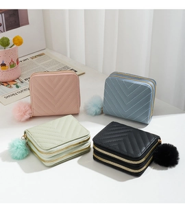 Detailed view of dual-layer wallets with chic twill stitching and soft pompom charms