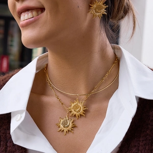 Detailed view of layered gold sun and moon necklaces and matching stud earrings