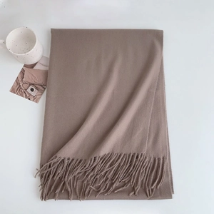 Flat lay of khaki faux cashmere scarf with fringe details on a minimalist white desk