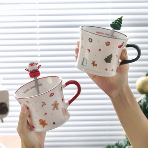 Detail of Christmas ceramic mugs with Santa spoons and festive gingerbread patterns