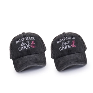 Close-up of dual washed charcoal baseball caps with BOAT HAIR embroidery on white background