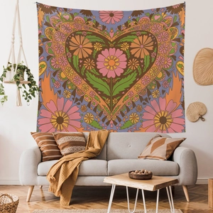 Bohemian floral heart tapestry hanging over a grey sofa in a cozy room setting